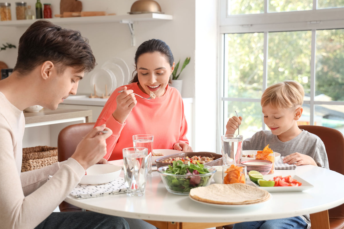 Parents and young son at a white dining table with glasses of tap water checked by a drinking water tester.
