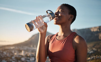 Woman hydrating with clean drinking water analyzed for contaminants using an at-home water testing kit.